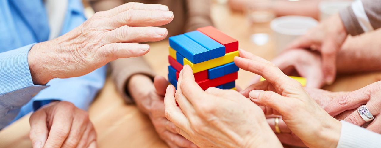 Hände, die Turm aus bunten Bausteinen bauen